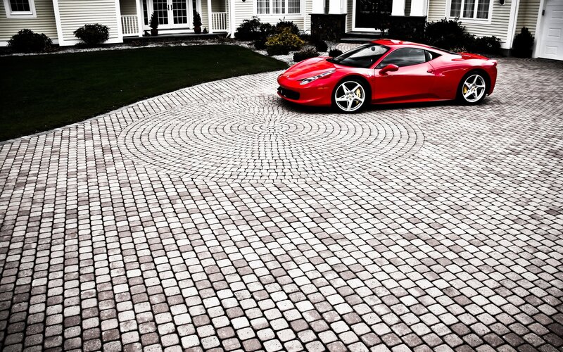Red sports car on cobblestone driveway