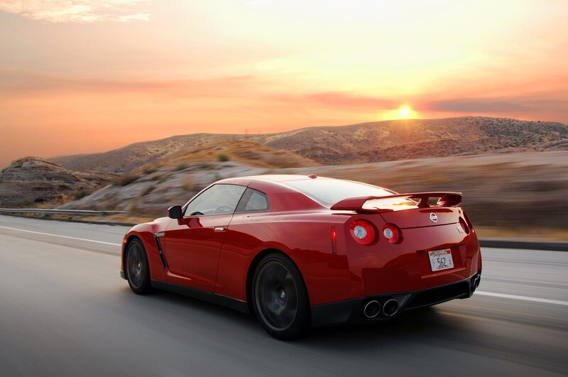 Red sports car on road at sunset