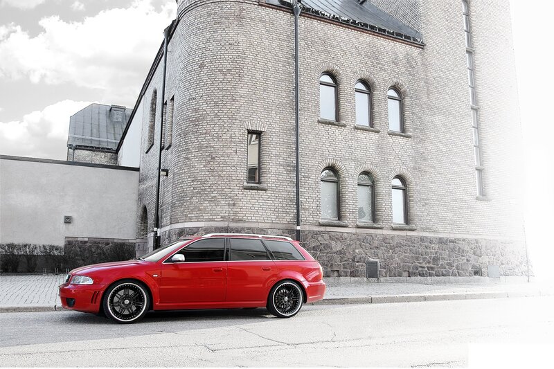 Red station wagon parked by brick building