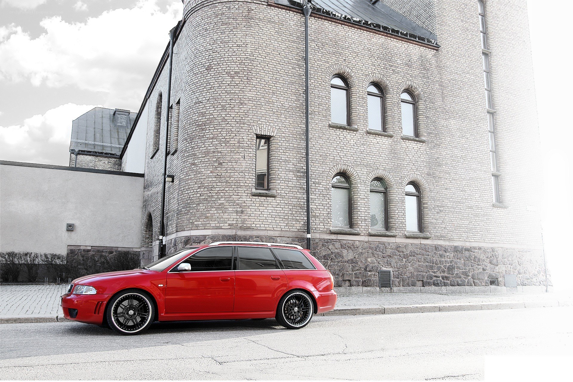 Red station wagon parked by brick building