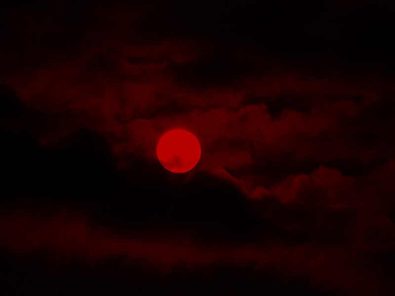Red sun in dark clouds