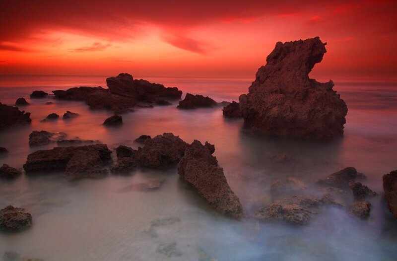Red sunset over rocky shore
