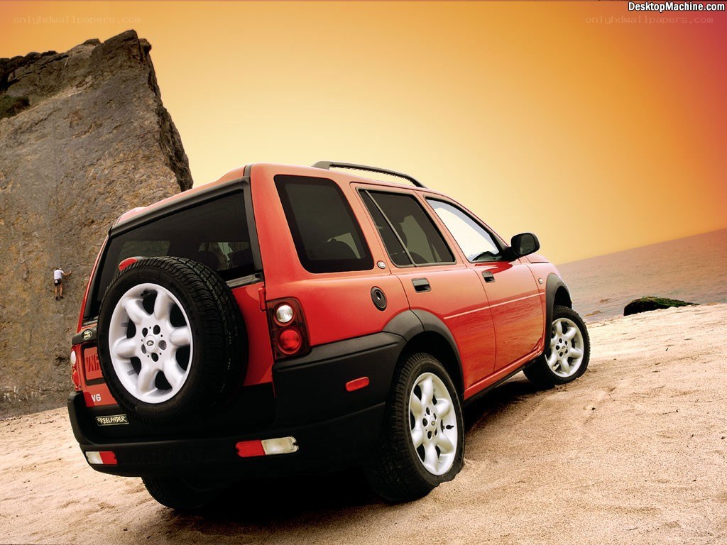Red SUV on beach at sunset