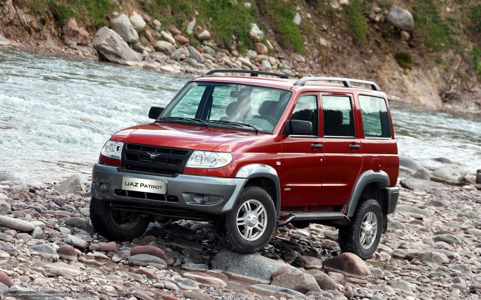 Red SUV on rocky riverbank