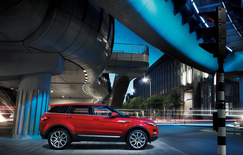 Red SUV under modern bridge