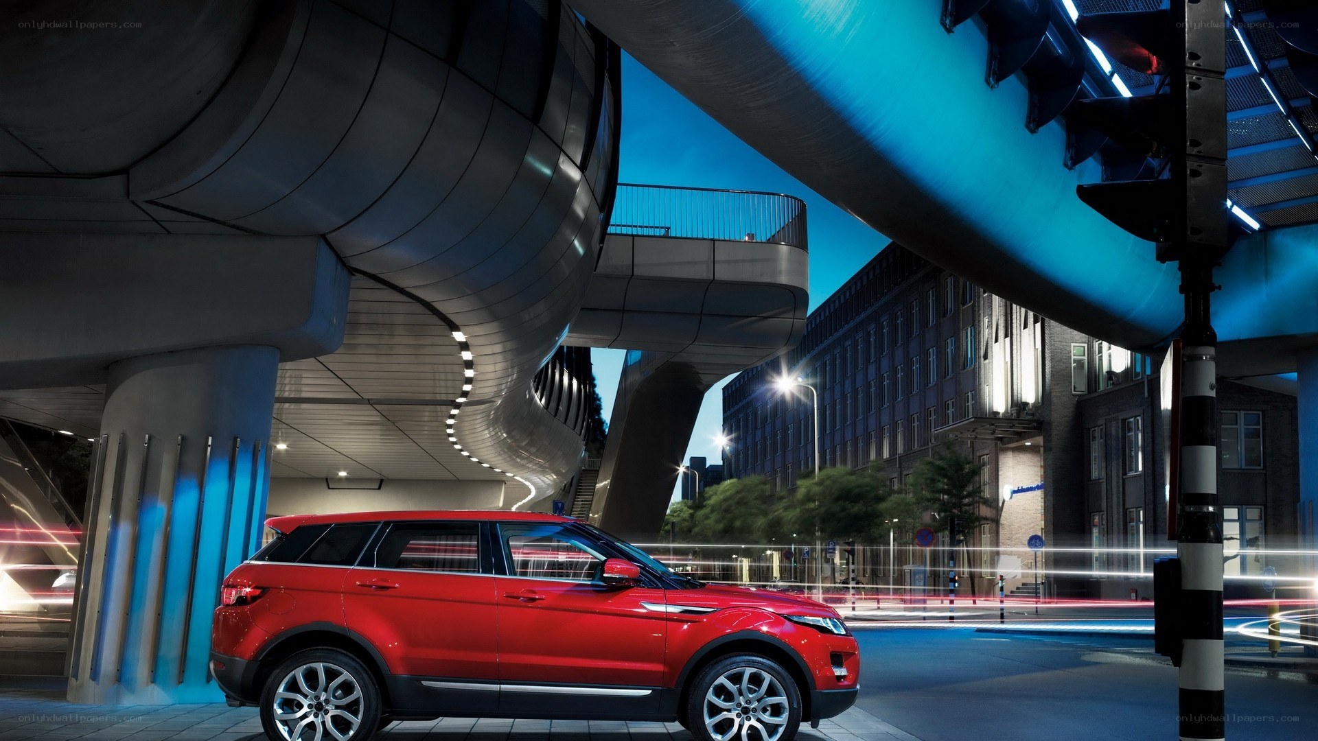 Red SUV under modern bridge