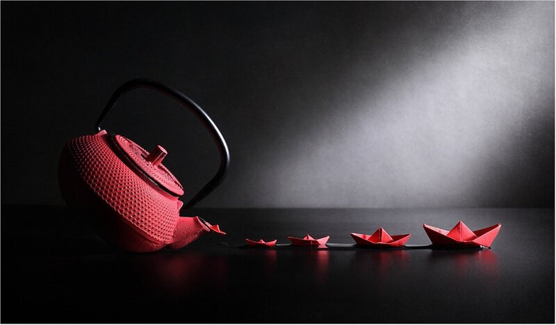 Red teapot with paper boats