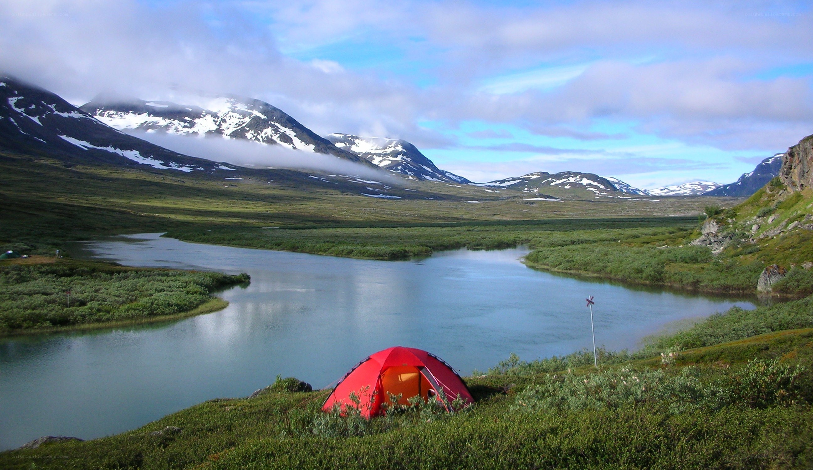 Red tent by a mountain lake