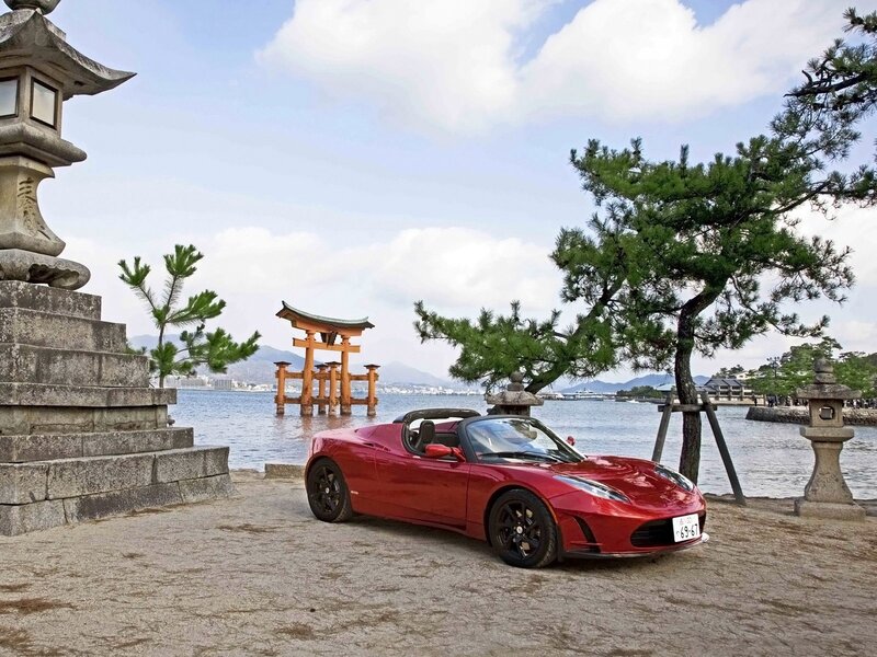 Red Tesla Roadster by the sea
