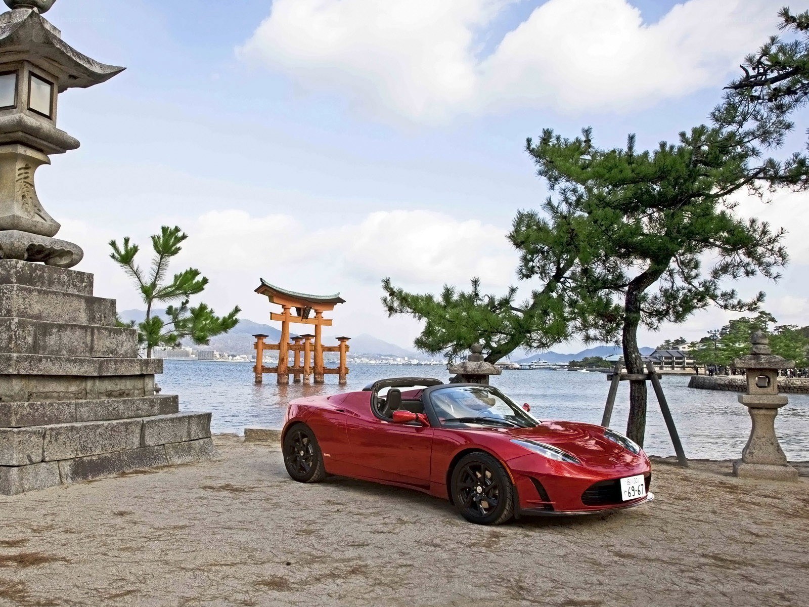 Red Tesla Roadster by the sea