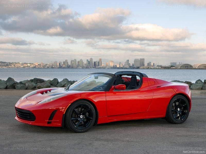 Red Tesla Roadster by waterfront
