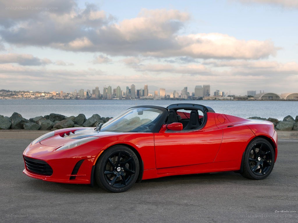 Red Tesla Roadster by waterfront