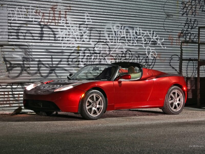 Red Tesla Roadster in front of graffiti wall