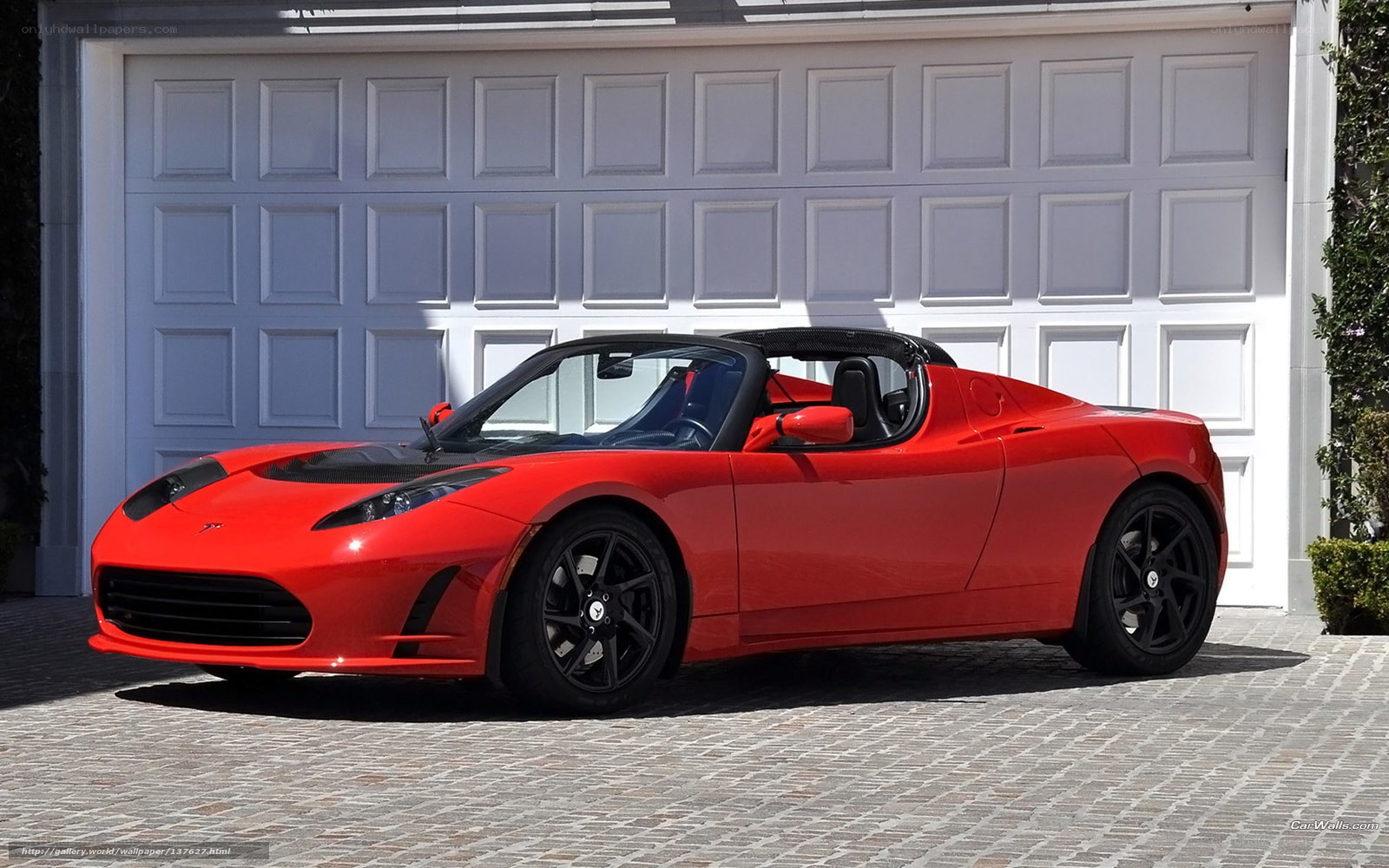 Red Tesla Roadster parked in driveway