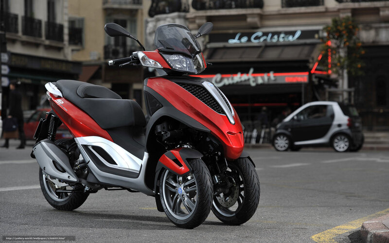 Red three-wheeled scooter on city street