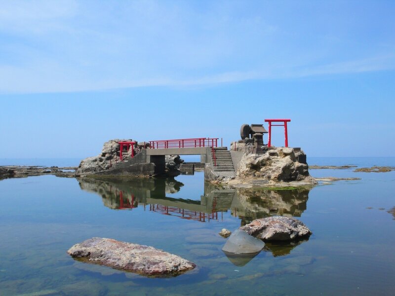Red torii gate on coastal rock