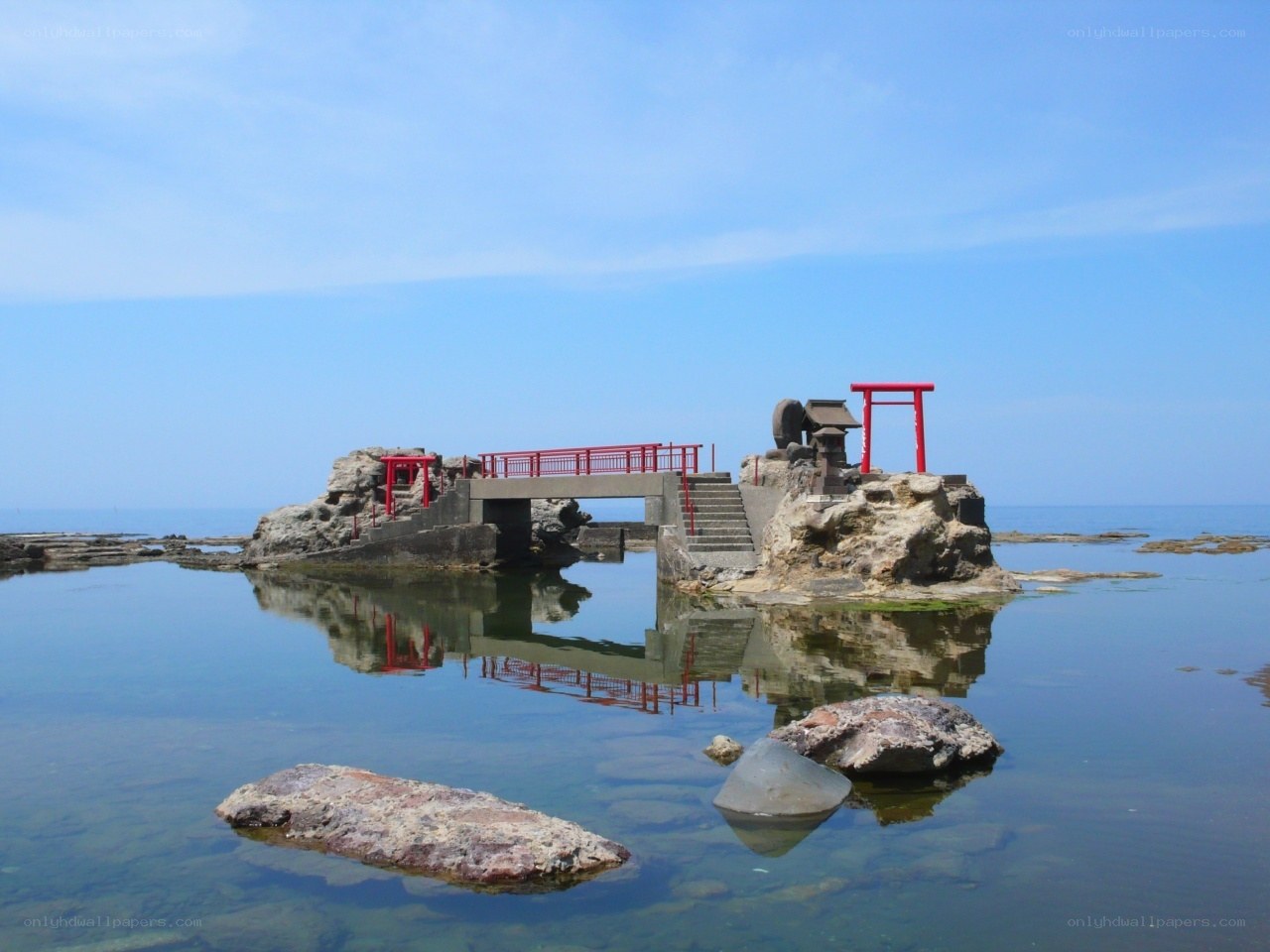 Red torii gate on coastal rock