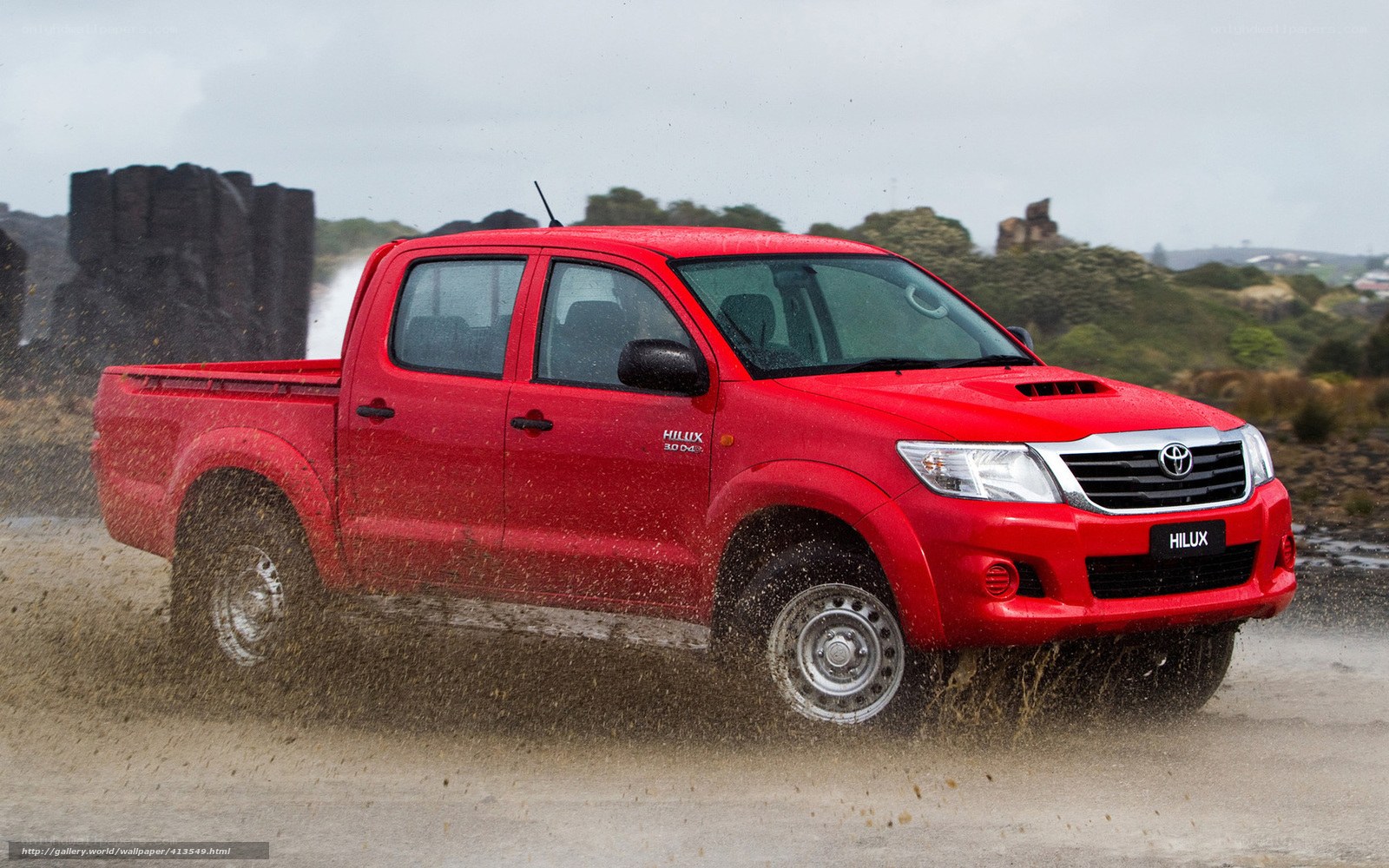 Red Toyota Hilux driving on dirt
