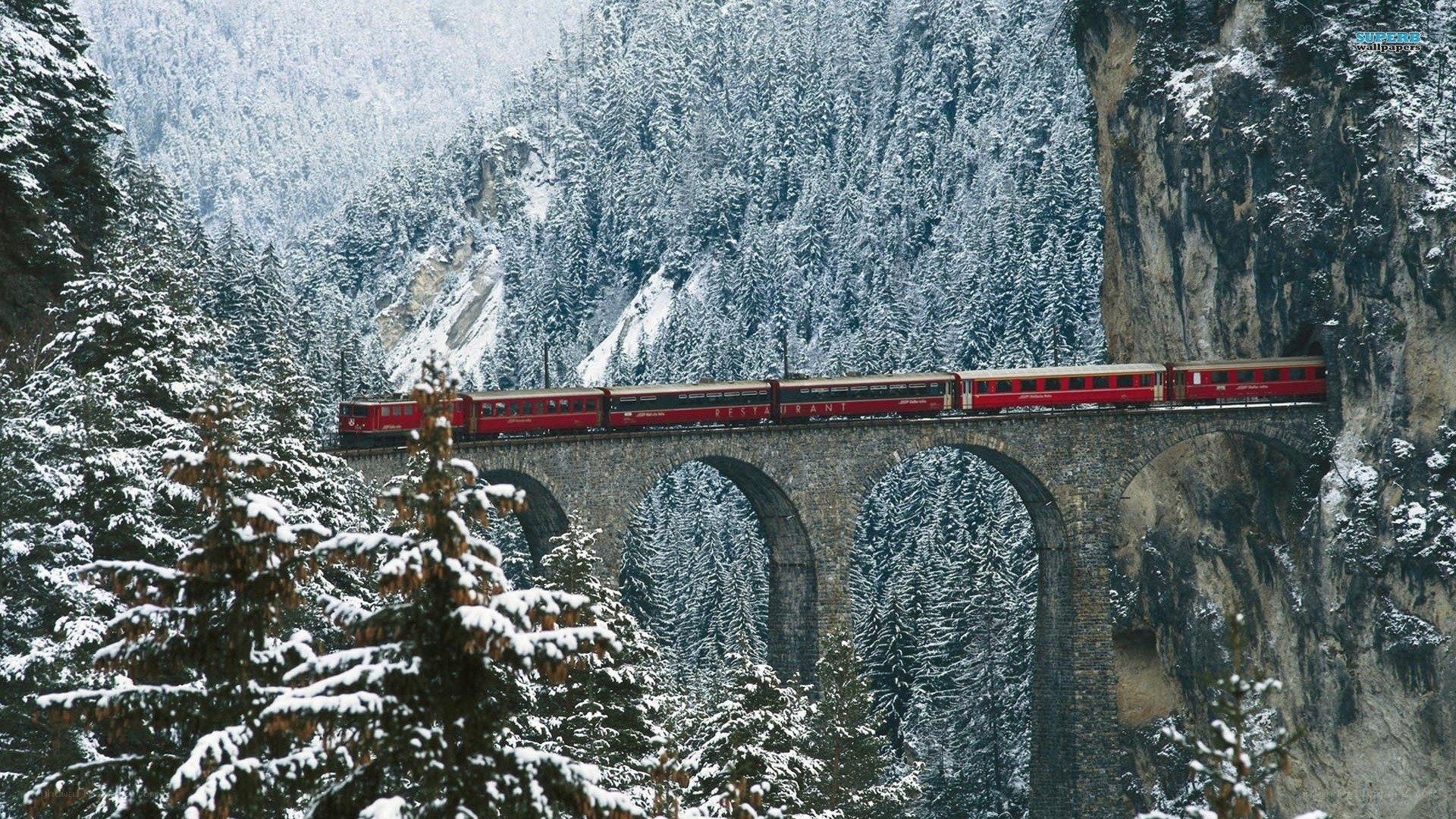 Red train on snowy bridge