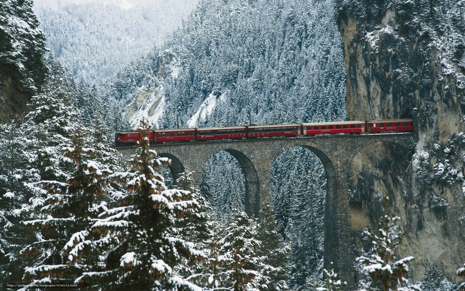Red train on snowy bridge