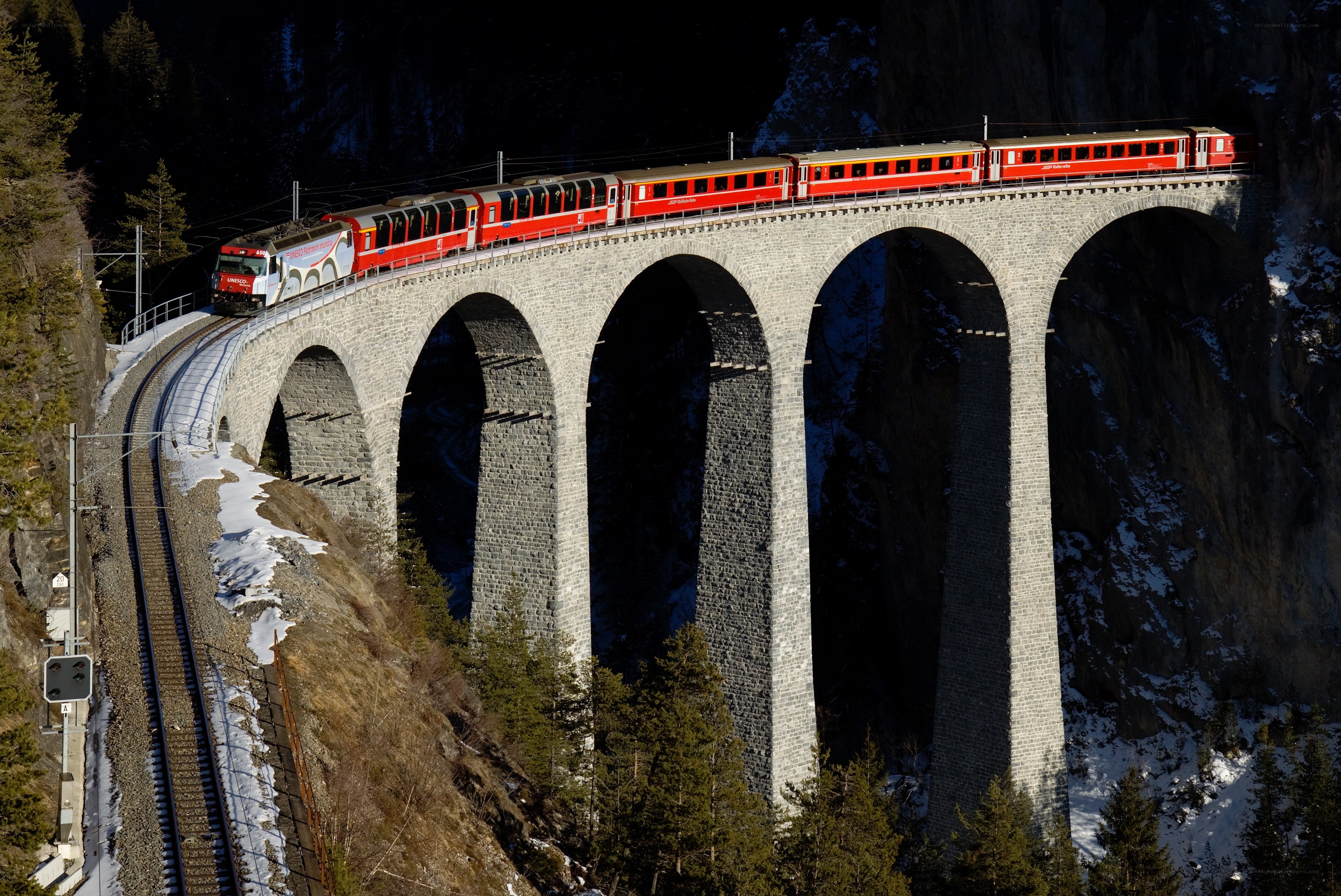 Red train on stone viaduct