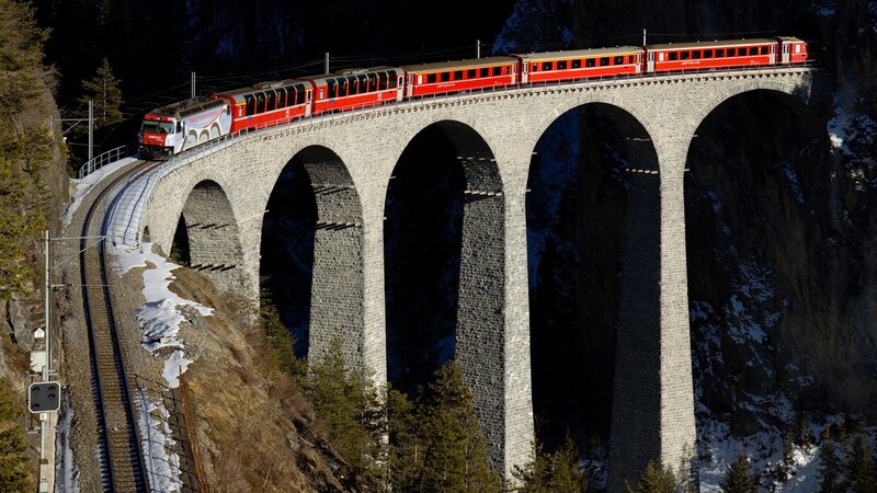 Red train on stone viaduct