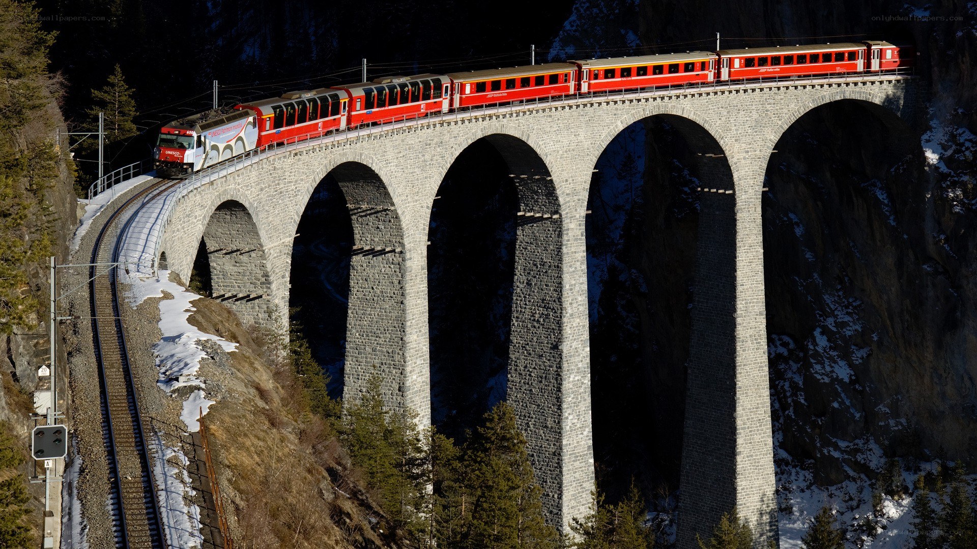 Red train on stone viaduct