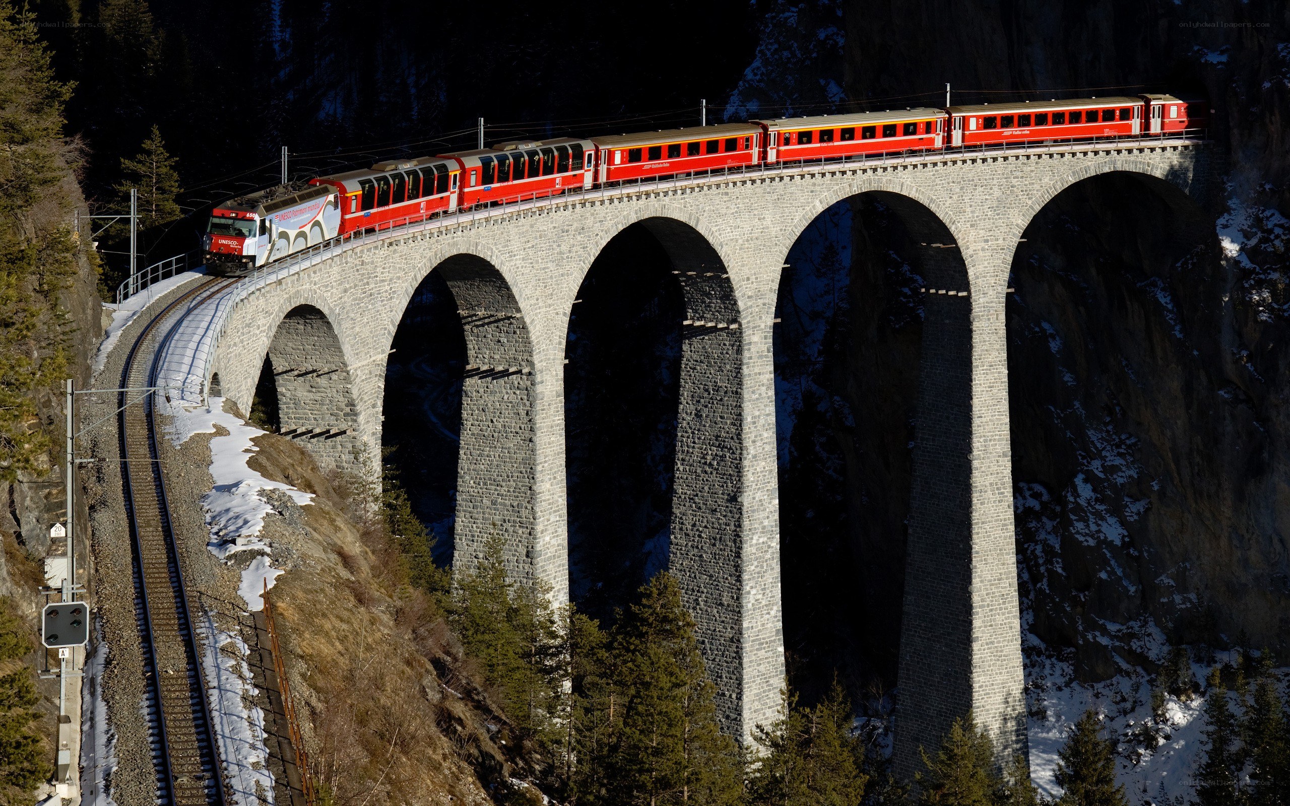 Red train on stone viaduct