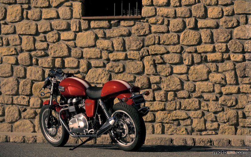 Red Triumph motorcycle against stone wall