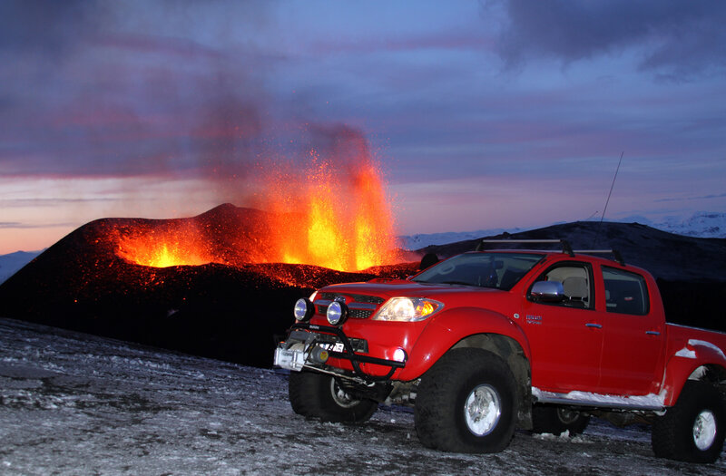 Red truck at erupting volcano