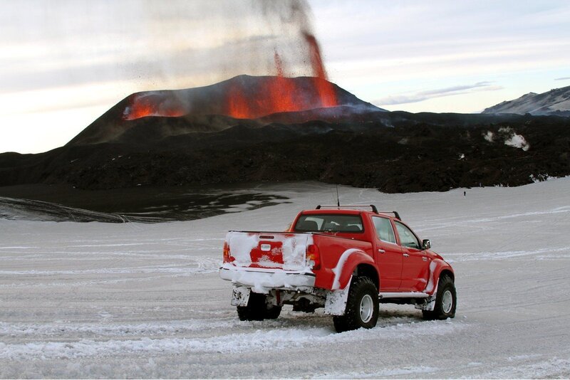 Red truck near erupting volcano