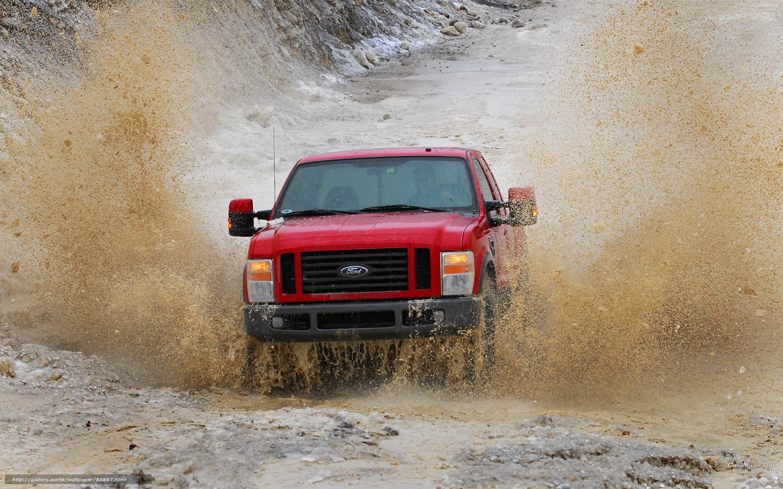 Red truck splashing through mud