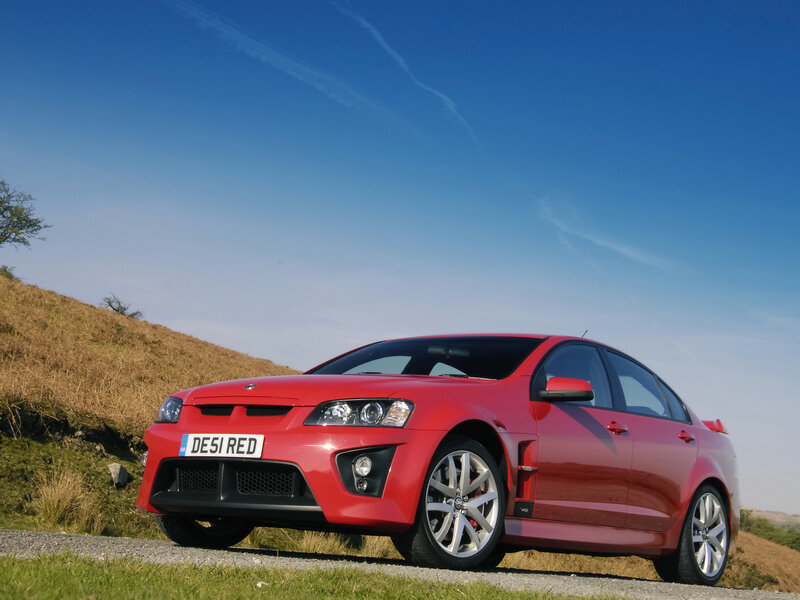 Red V8 sedan on a hill