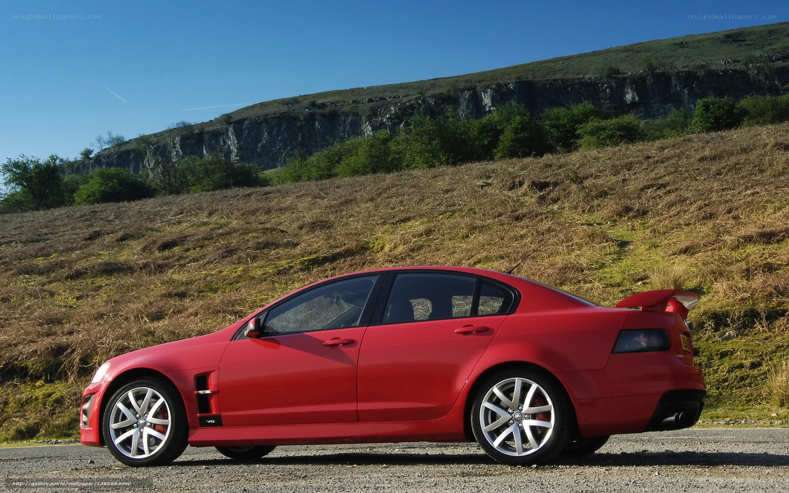 Red V8 sedan on a hillside