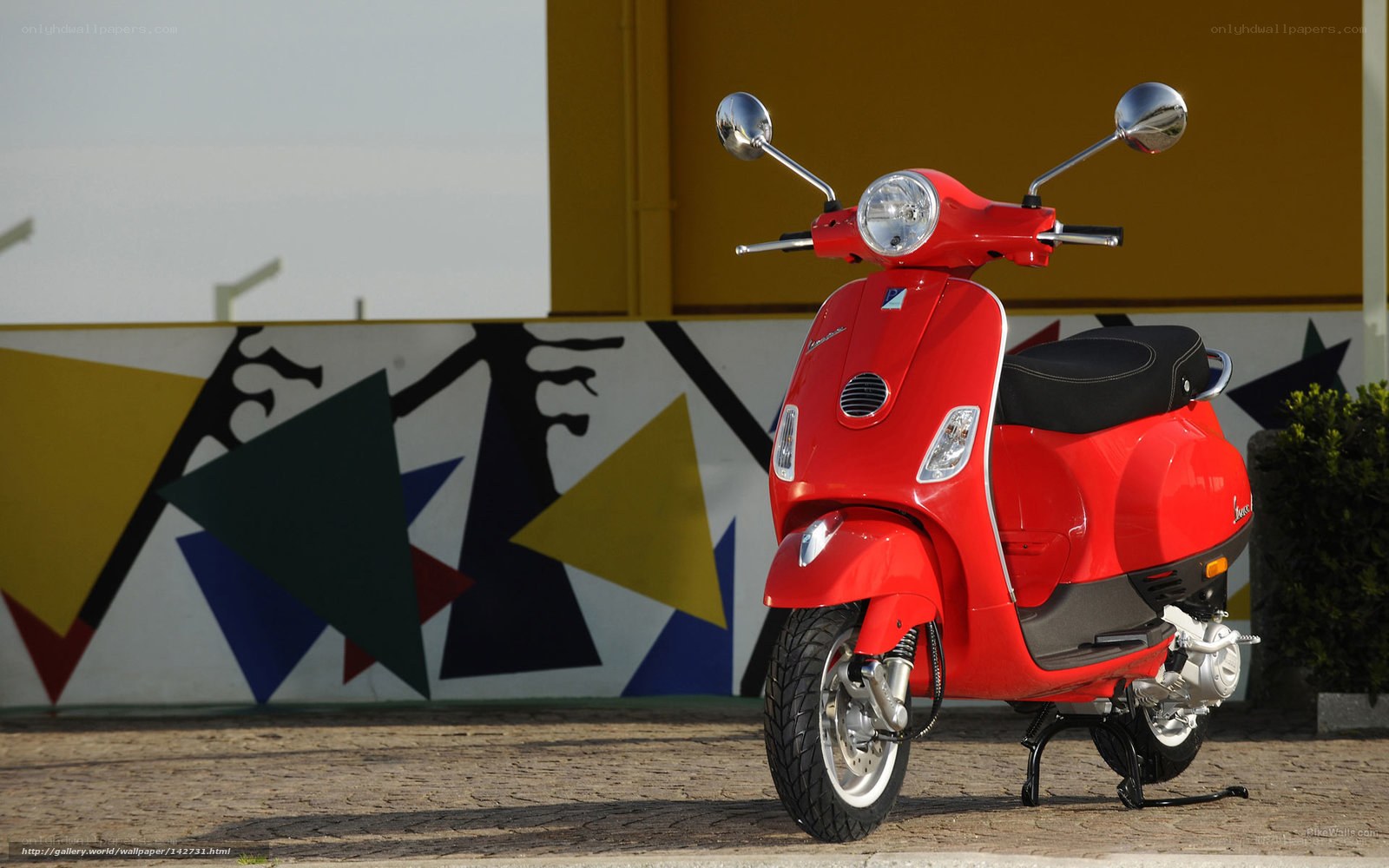 Red Vespa scooter on cobblestone