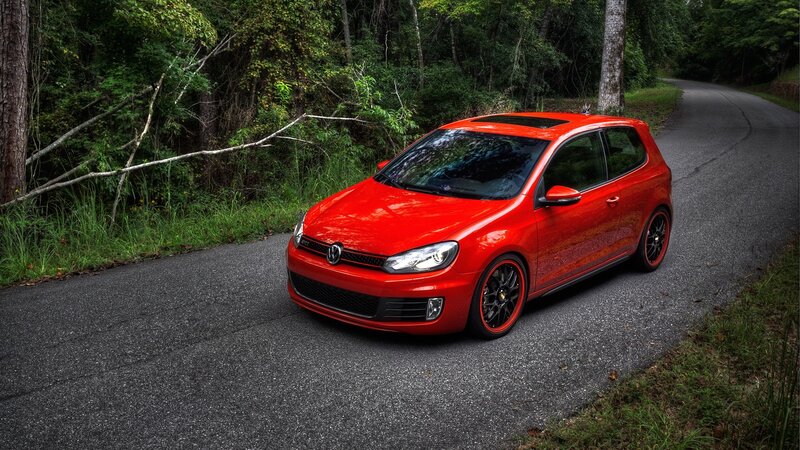 Red Volkswagen Golf on forest road