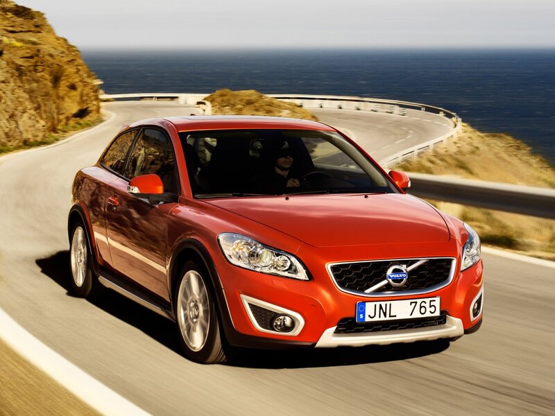 Red Volvo C30 driving on coastal road