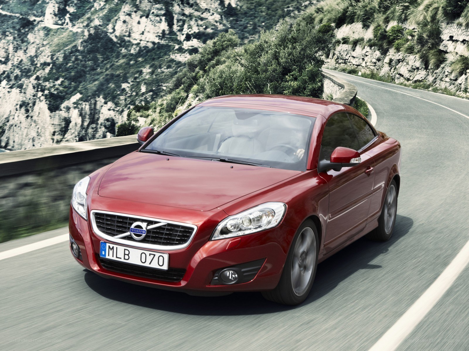 Red Volvo C70 driving on mountain road