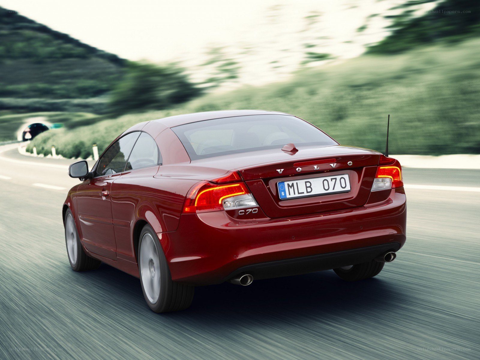 Red Volvo C70 driving on road
