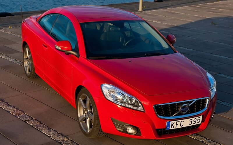 Red Volvo C70 parked by water