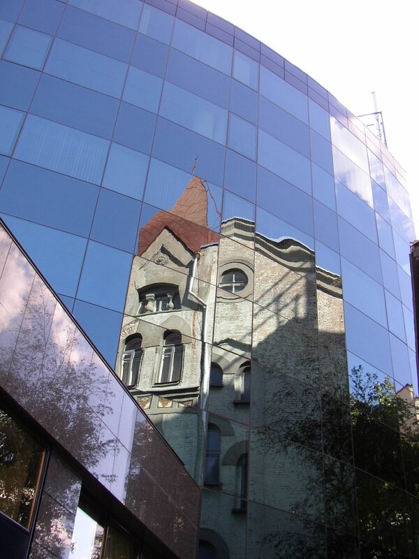 Reflection of old building on glass facade