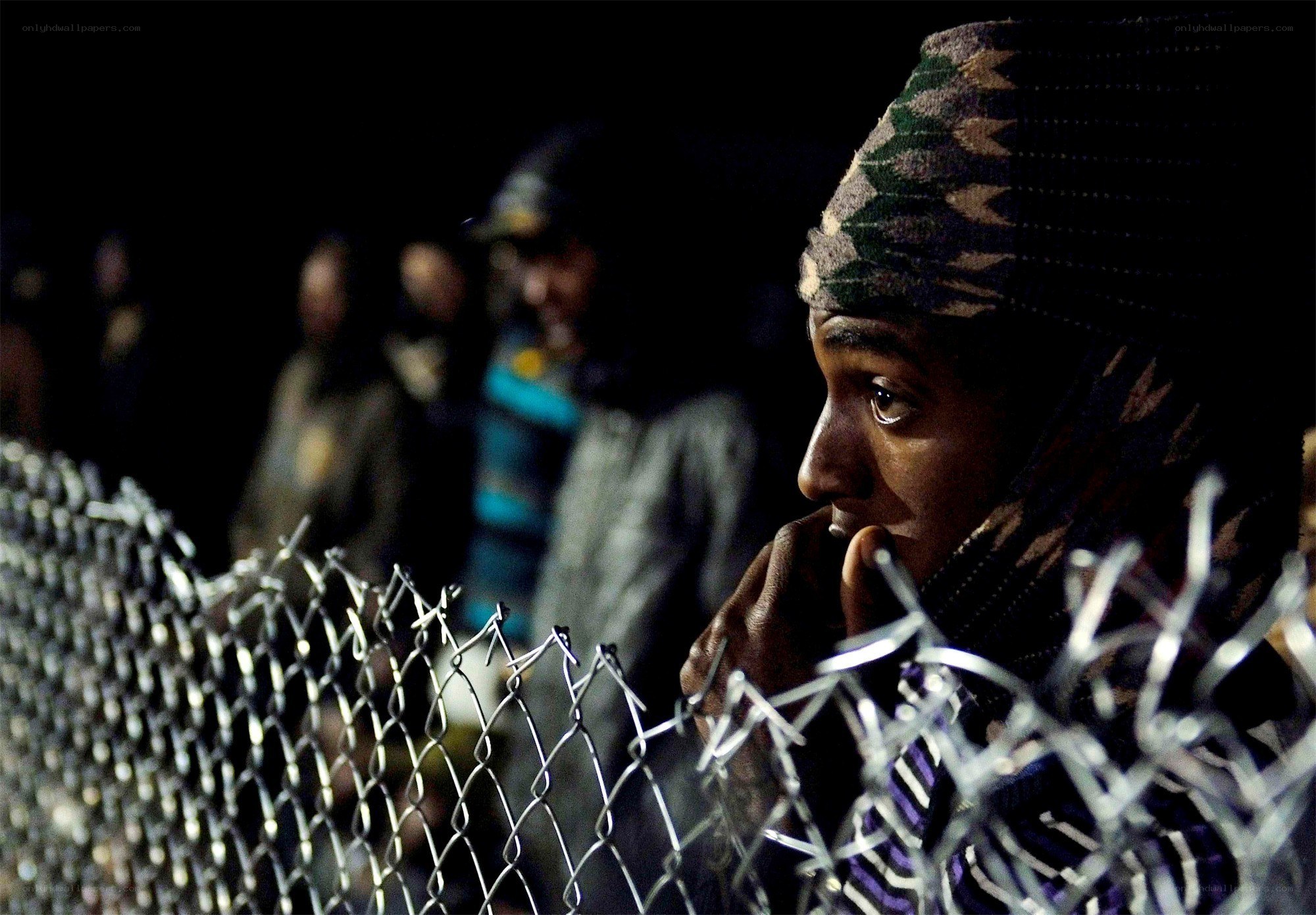 Refugee behind a fence at night