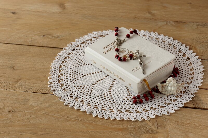 Religious book and rosary on doily
