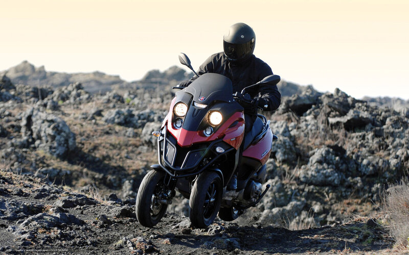 Rider on red scooter in rocky terrain
