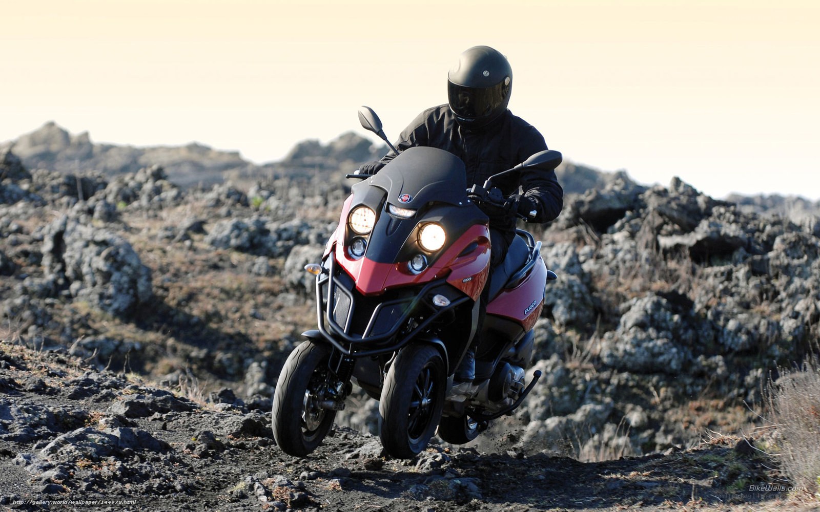 Rider on red scooter in rocky terrain