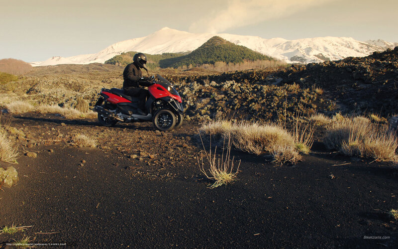 Rider on red scooter in volcanic landscape