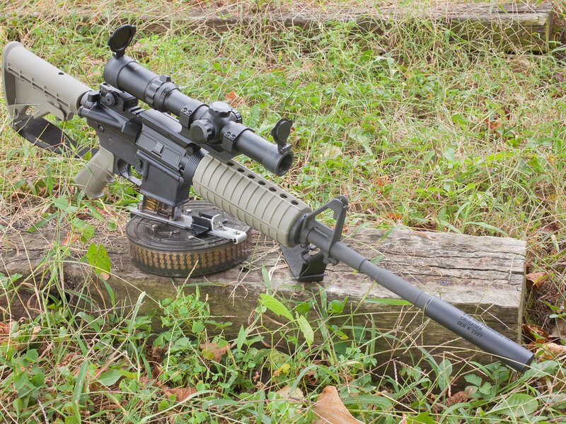 rifle with scope on log