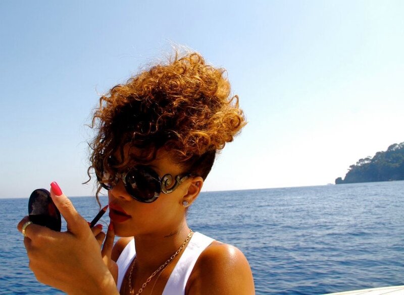 Rihanna applying lipstick on a boat