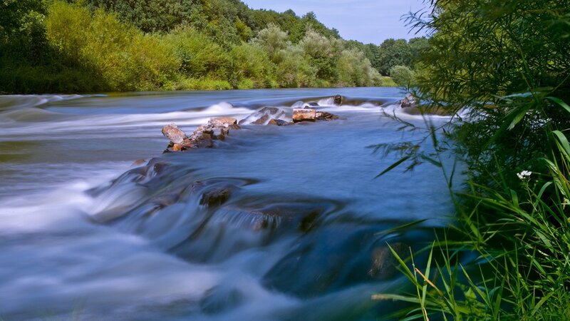 River Flowing over Rocks — Blue, Serene, Afternoon, Photograph, Trees, Grass, Green