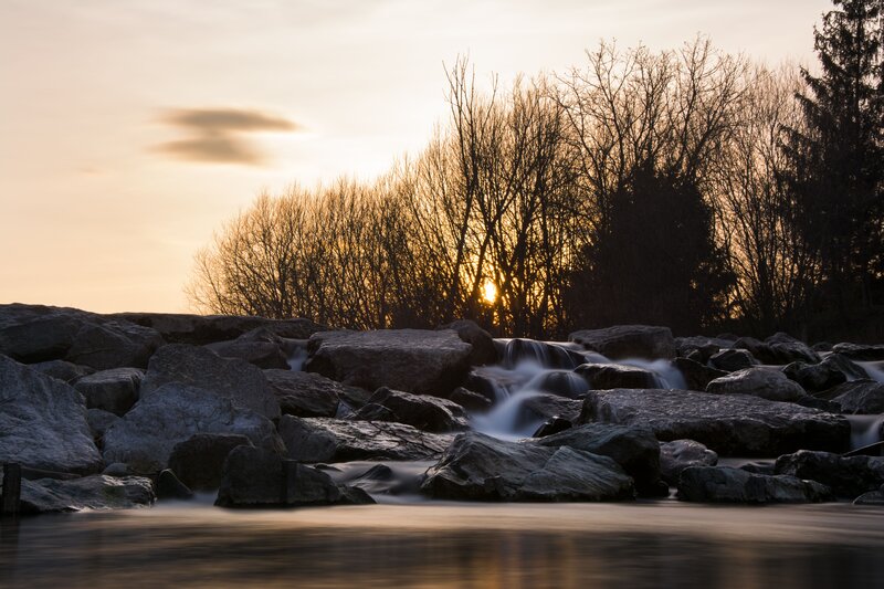River Flowing over Rocks — Gray, Serene, Sunset, Photograph, Trees